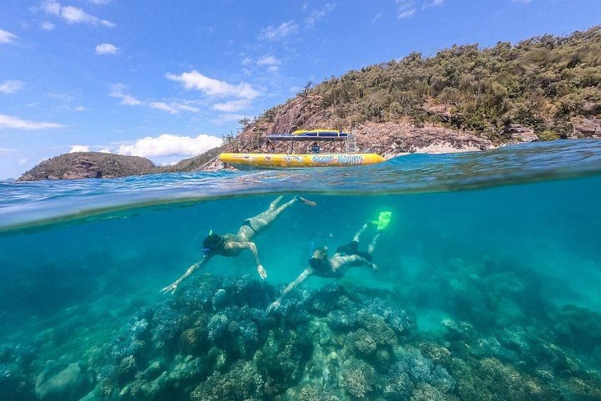 Two people snorkeling underwater with a boat in the background. 2