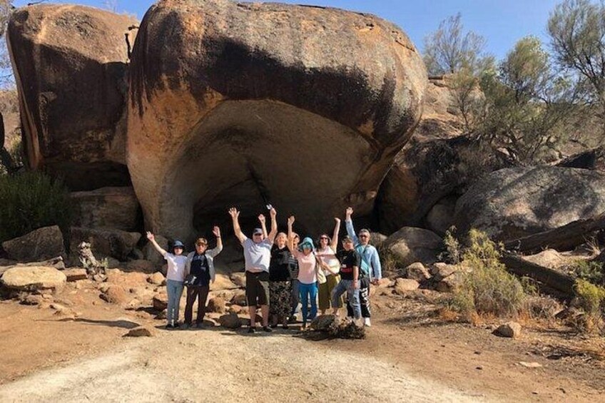 Un groupe de personnes se tient devant une grande formation rocheuse. 3