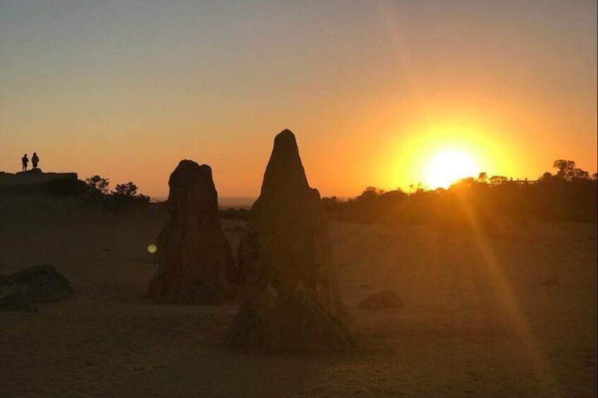 A sunset over a desert landscape with two prominent rock formations. 5