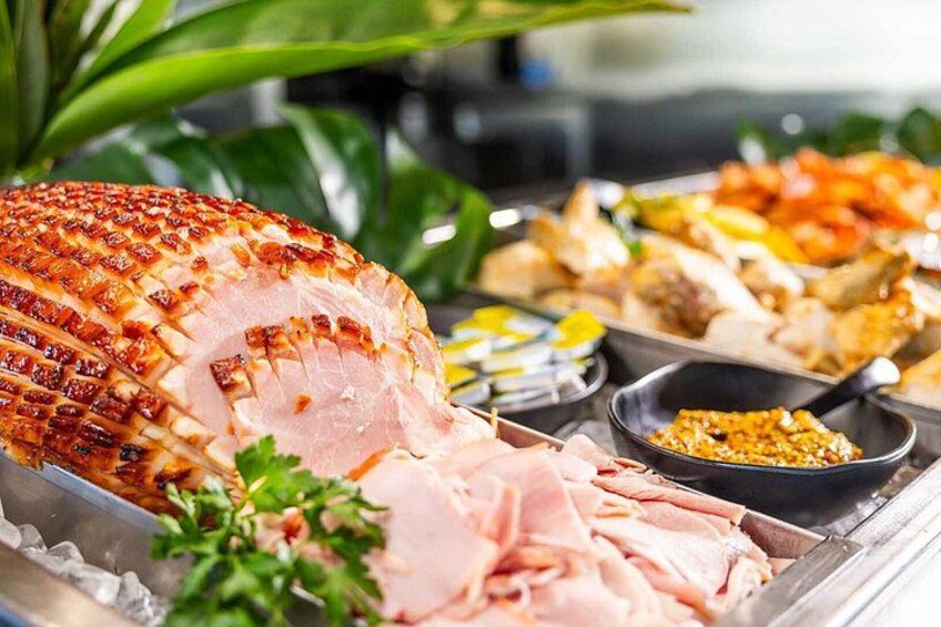 Un jamón asado con piel crujiente, carne en rodajas y diversos acompañamientos en una bandeja. 3