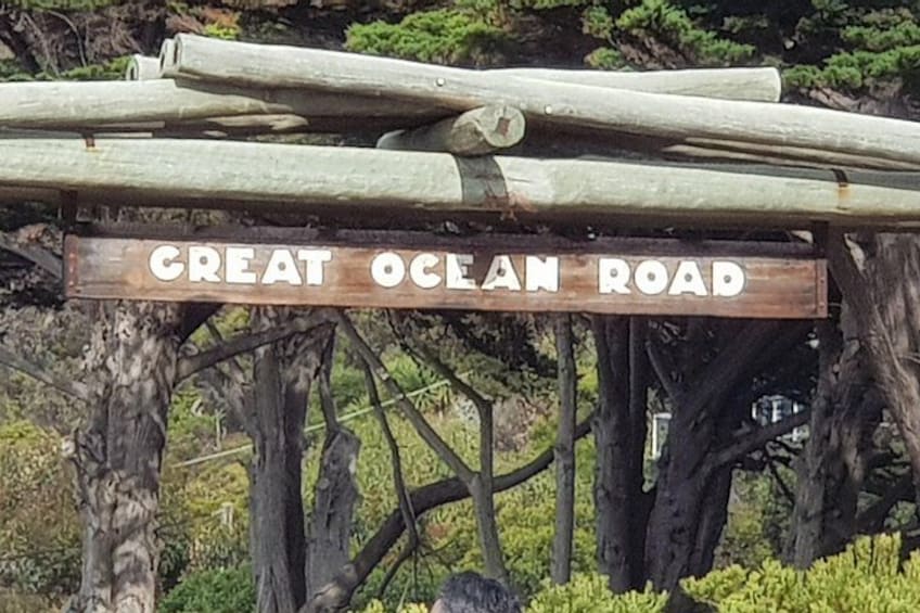 A wooden sign with the text 'GREAT OCEAN ROAD' mounted on a wooden structure. 5