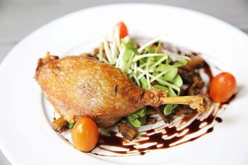 A roasted chicken leg with sprouts and cherry tomatoes on a plate. 2