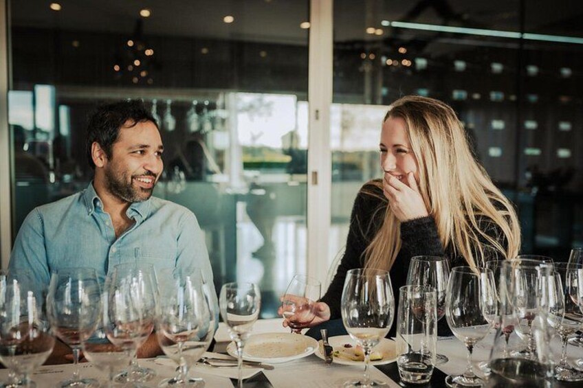 Two people dining at a restaurant with multiple wine glasses on the table. 2