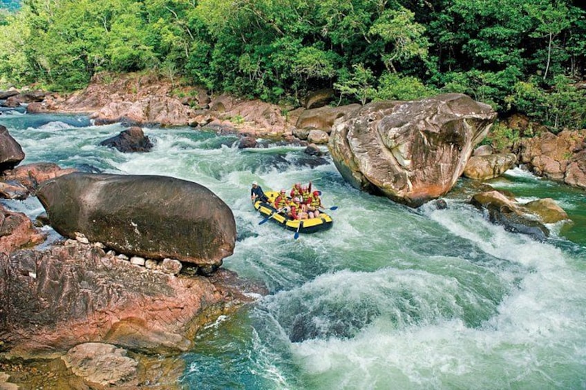 A river with rapids, large rocks, and a raft with people. 2