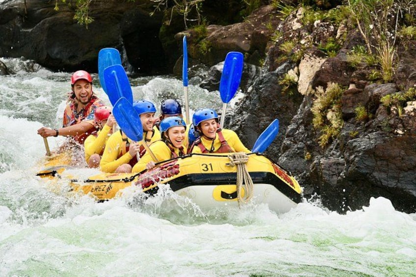 Un groupe de personnes à bord d’un radeau jaune, avec des pagaies bleues, navigue sur une rivière. 2