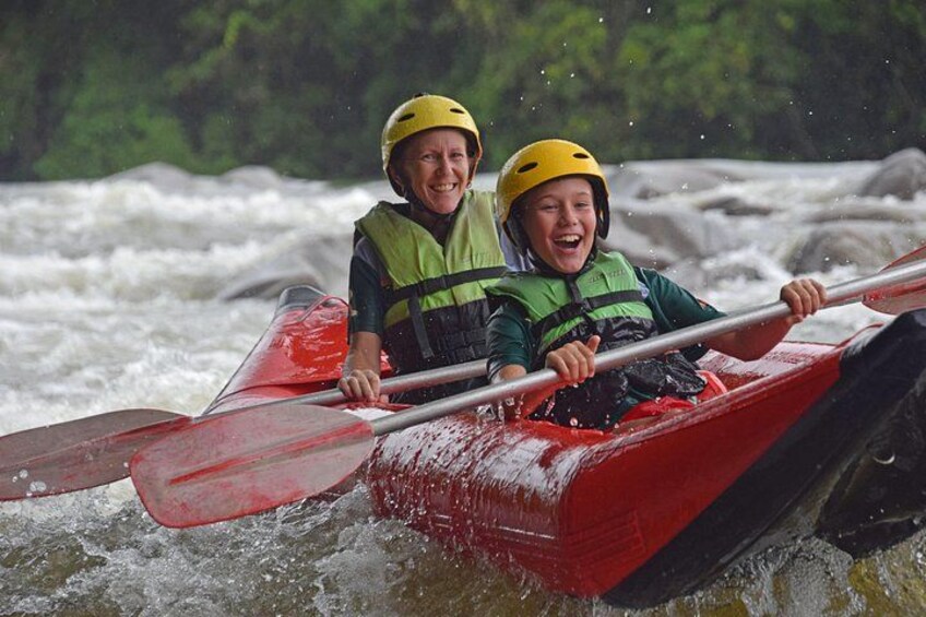 Two people in a red kayak navigating a river. 5