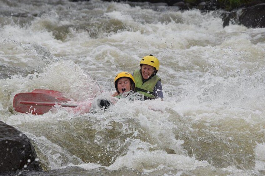 Two people in a white kayak navigating rough waters. 4