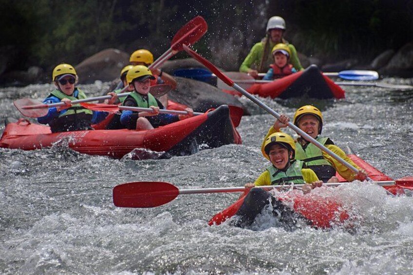 People in red kayaks paddling on a river. 3
