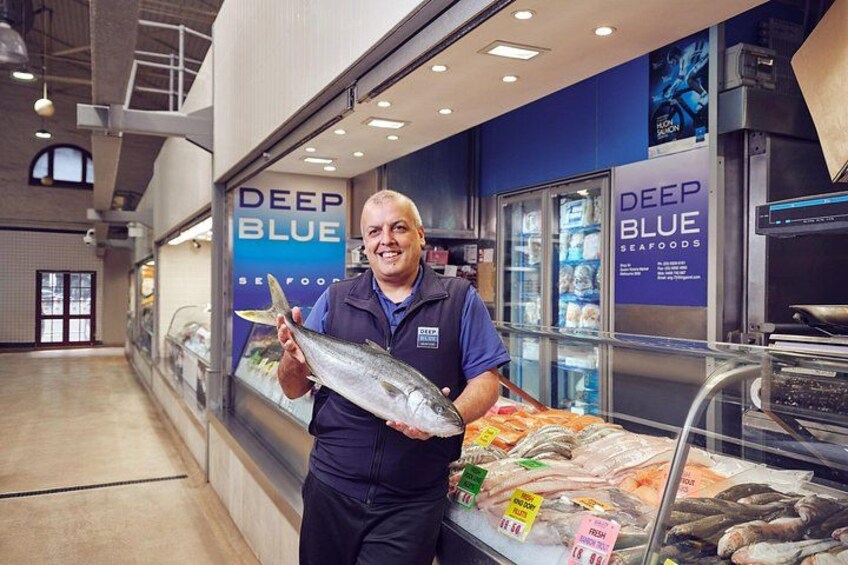 A seafood display with a man holding a fish, a refrigerated case, and a sign that reads 'DEEP BLUE SEAFOODS'. 2
