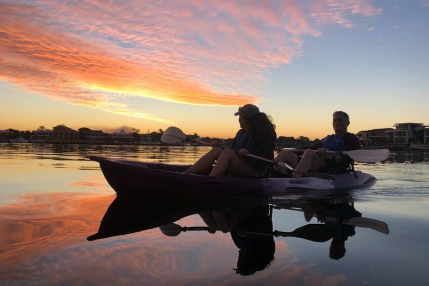 Two people in a boat on a calm body of water during sunset. 4