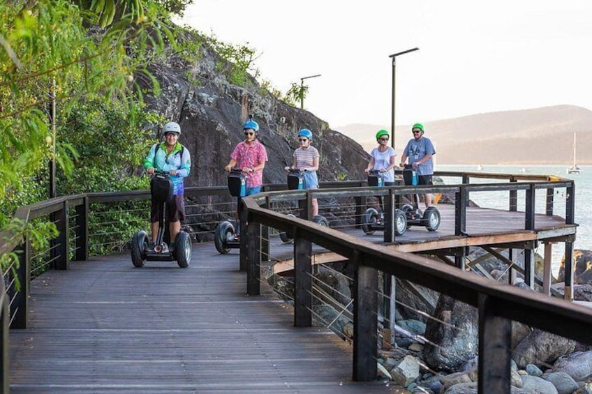A wooden boardwalk with people riding Segways. 3