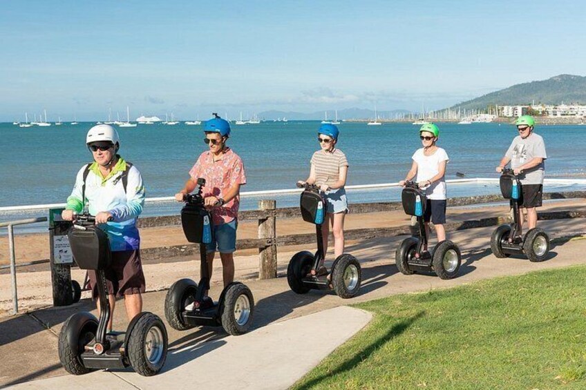 People riding Segways along a waterfront path. 4