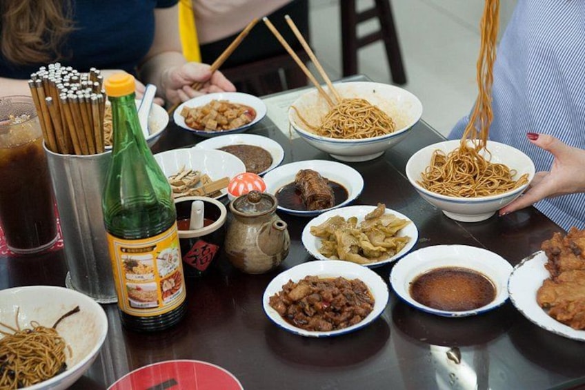 A table with various dishes, chopsticks, and a bottle. 2