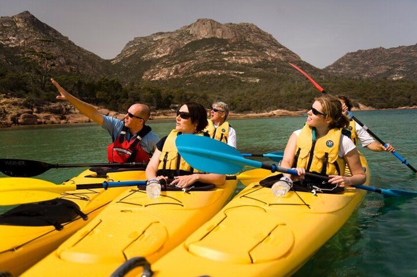 Un groupe de personnes pratiquant le kayak sur une rivière, avec des montagnes en arrière-plan. 2