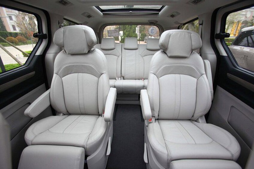 A vehicle interior with white leather seats, a central console, and a sunroof. 3