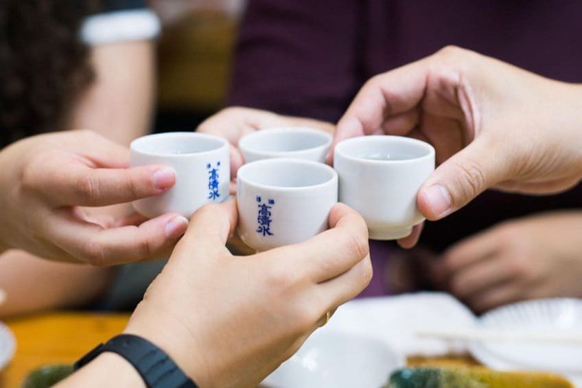 A group of people holding white cups with blue characters, likely participating in a traditional tea ceremony. 2