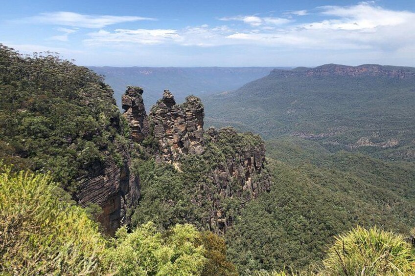 A mountainous landscape with prominent rock formations and dense green vegetation. 3