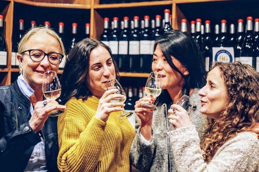 A group of people toasting with wine glasses in a wine cellar. 2