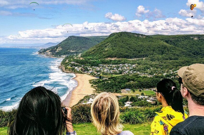 A coastal landscape with a beach, hills, and a view of the ocean. 1