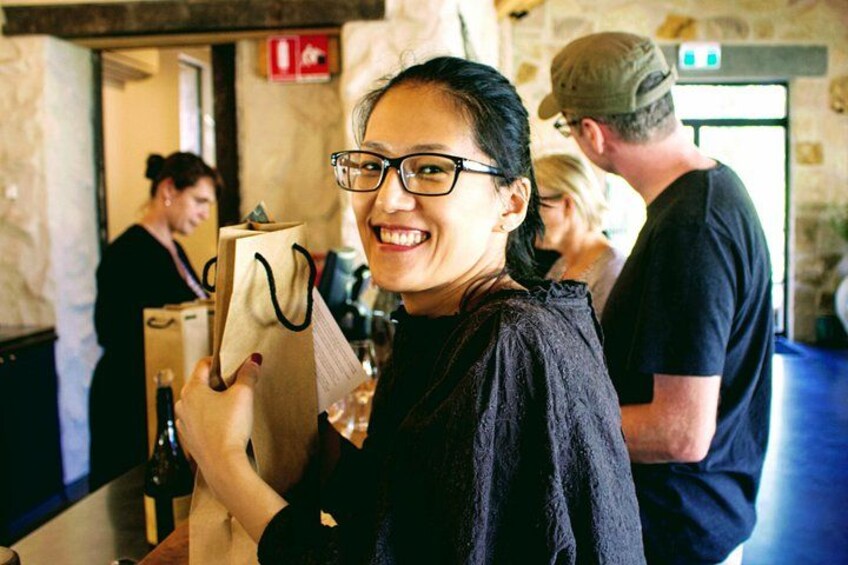 A person holding a paper bag, a wine bottle, and a glass. 2