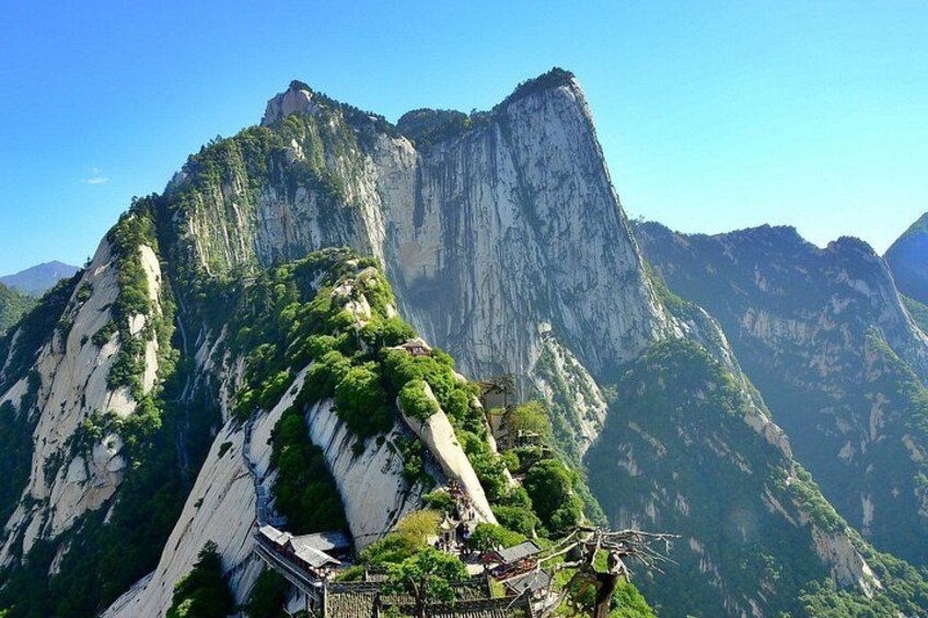 A mountain with a temple on its peak, lush greenery, and steep cliffs. 4