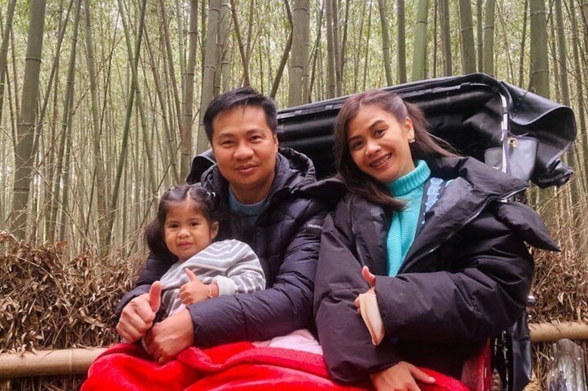 A family seated on a bench in a bamboo forest. 1