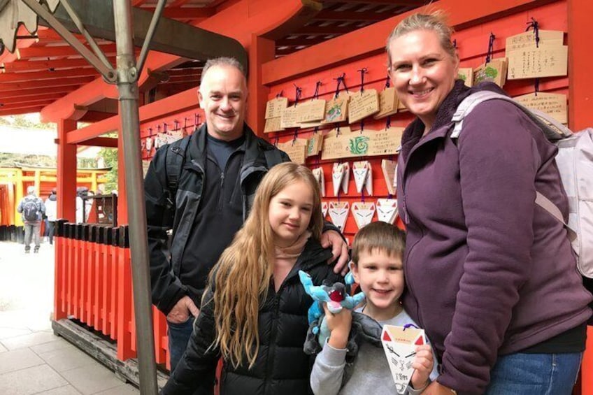 A family at a shrine with red torii gates and wooden plaques. 5