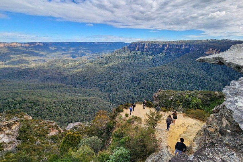 A mountainous landscape with a group of people hiking on a trail. 3