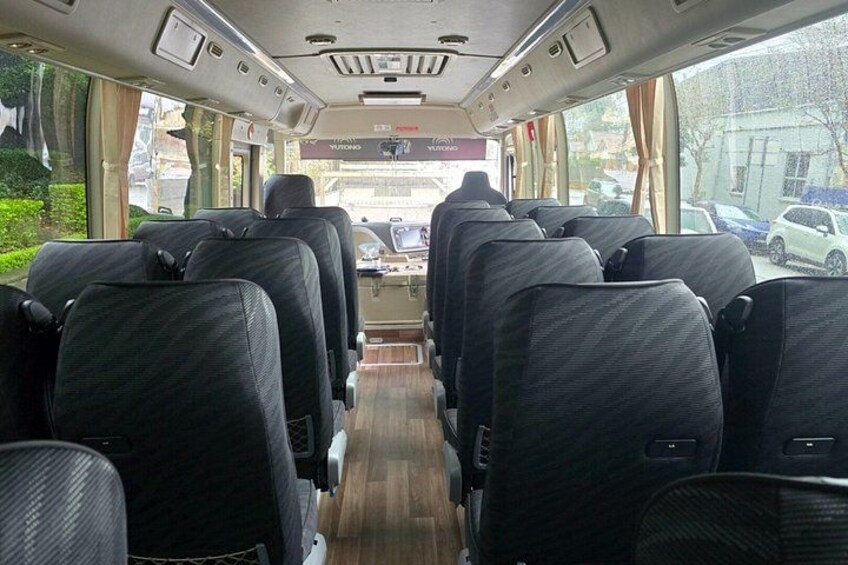 Interior de autobús con hileras de asientos, piso de madera y parte delantera con ventanas. 2