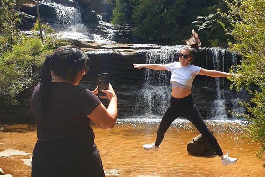 A person jumping in front of a waterfall. 5