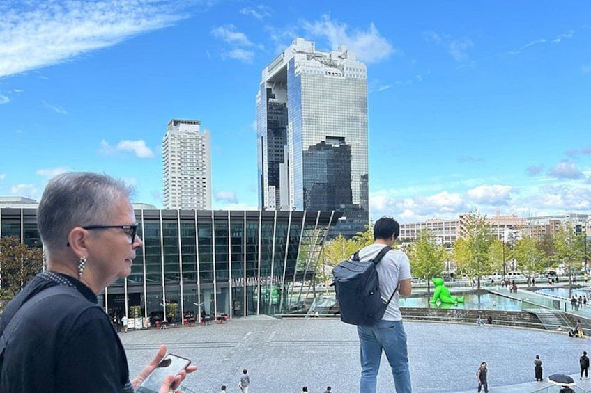 A cityscape with modern buildings, a clear sky, and a few people walking. 5