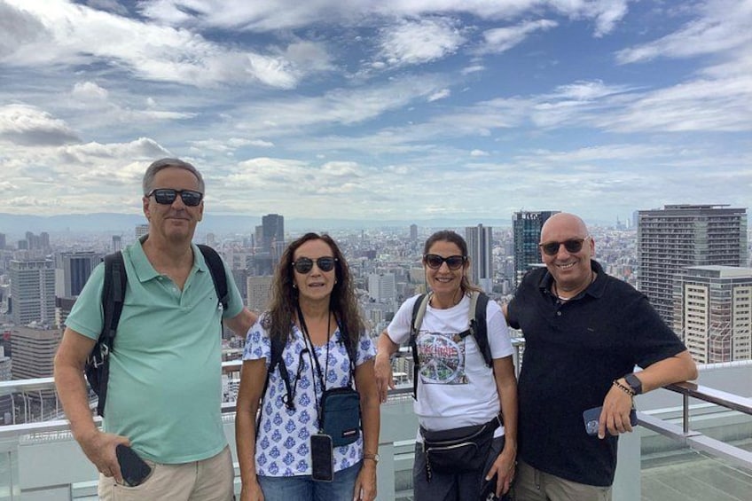 A group of people standing on a rooftop with a city skyline in the background. 3