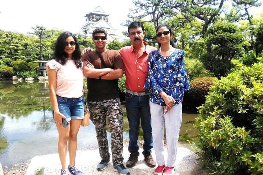 A group of people standing by a pond with a pagoda in the background. 1
