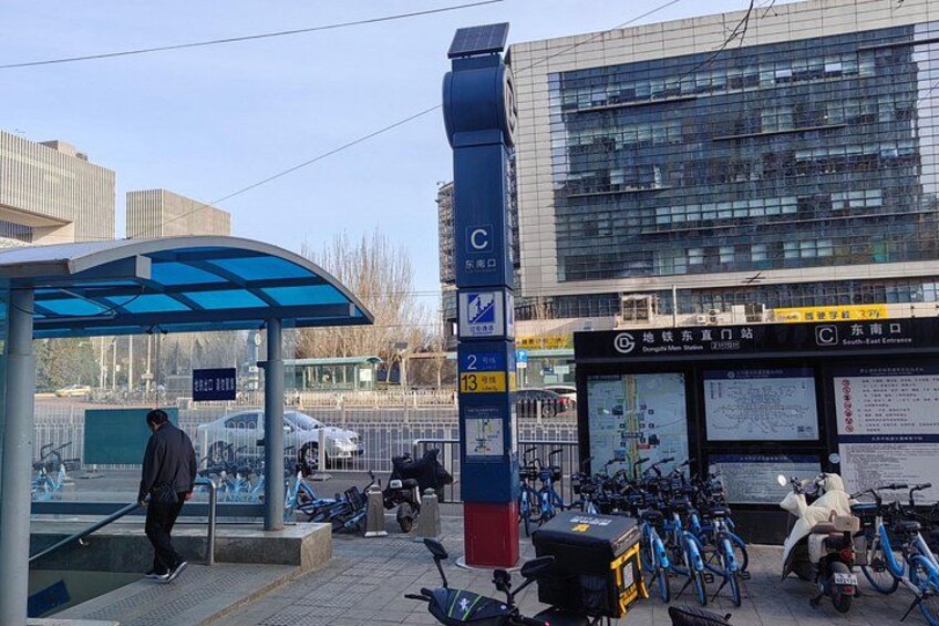 Un arrêt de bus avec un abri bleu, un grand poteau couvert de publicités et plusieurs vélos garés. 4
