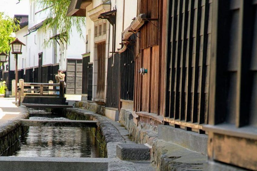Une rue typique du Japon, bordée de lanternes en pierre, de clôtures en bois et d’un petit canal. 1