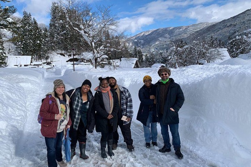 Un groupe de personnes se tient debout dans un paysage enneigé, avec des arbres et des montagnes en arrière-plan. 4
