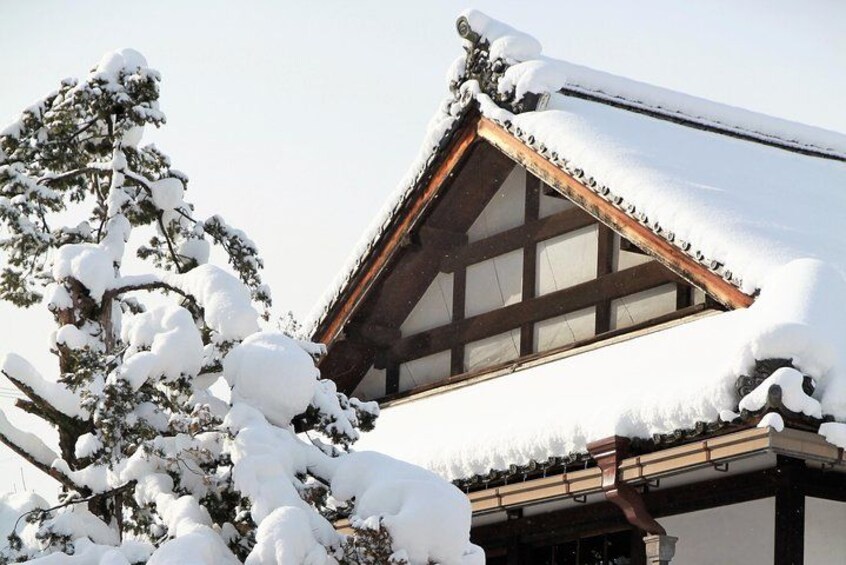 Ein traditionelles japanisches Gebäude mit einem schnee bedeckten Dach und Fenstern. 3