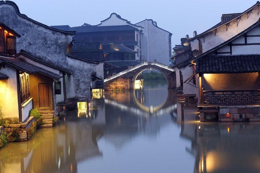 A traditional Chinese water town at dusk with illuminated buildings and a clear reflection in the water. 5