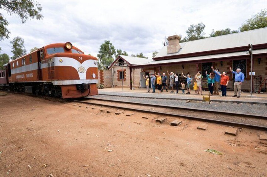 Un tren antiguo en una estación, con personas de pie en el andén. 3