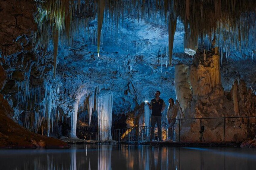 A cave with stalactites and stalagmites, illuminated by artificial lighting. 1
