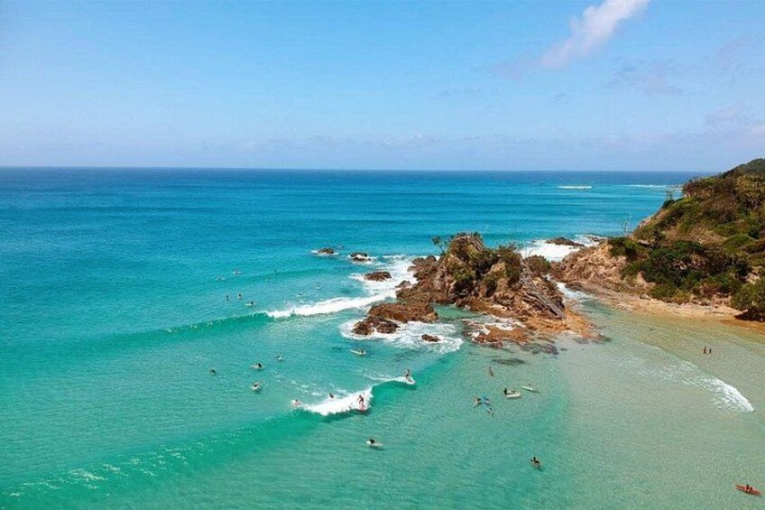 A coastal landscape with clear turquoise waters, rocky outcrops, and a sandy beach. 2