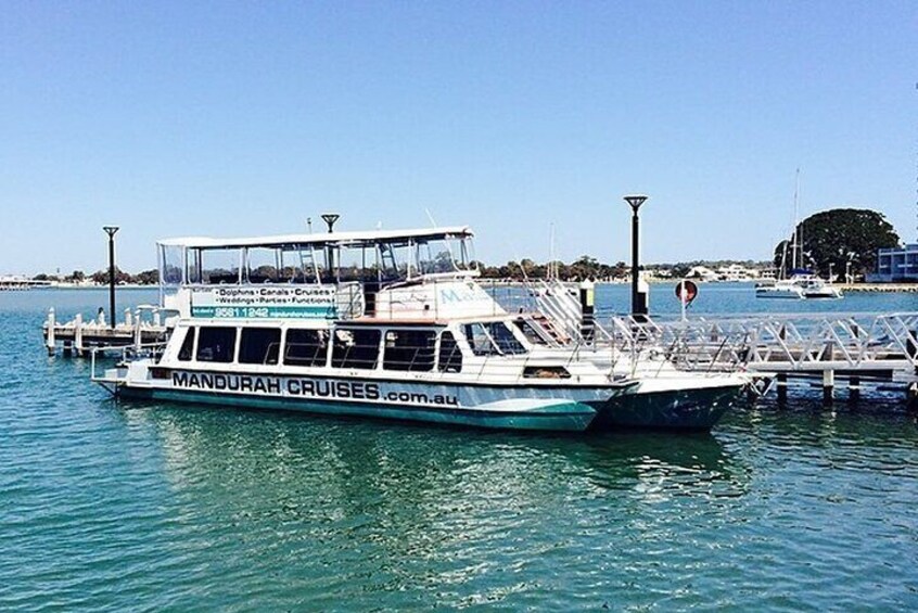 A boat docked at a pier with the text "MANDURAH CRUISES.com.au" on its side. 3