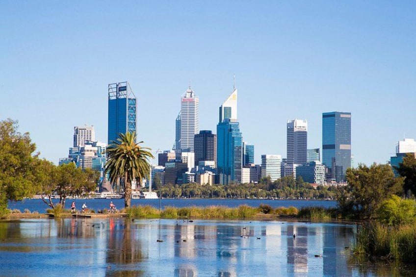 A city skyline with modern skyscrapers, a body of water reflecting the buildings, and a palm tree in the foreground. 5