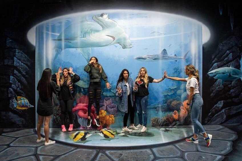 A group of people standing in front of an aquarium exhibit with marine life. 3