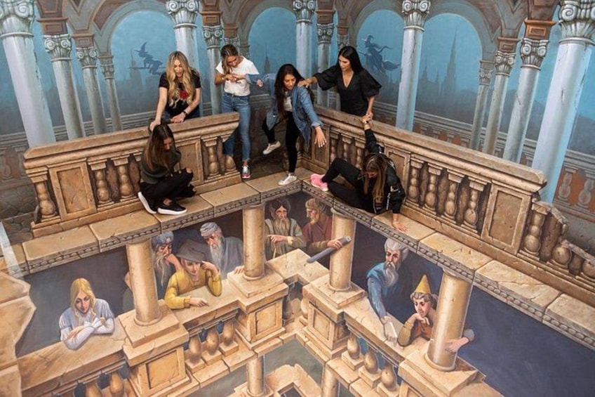 A group of people sitting on a balcony overlooking a detailed mural of historical figures and architecture. 2