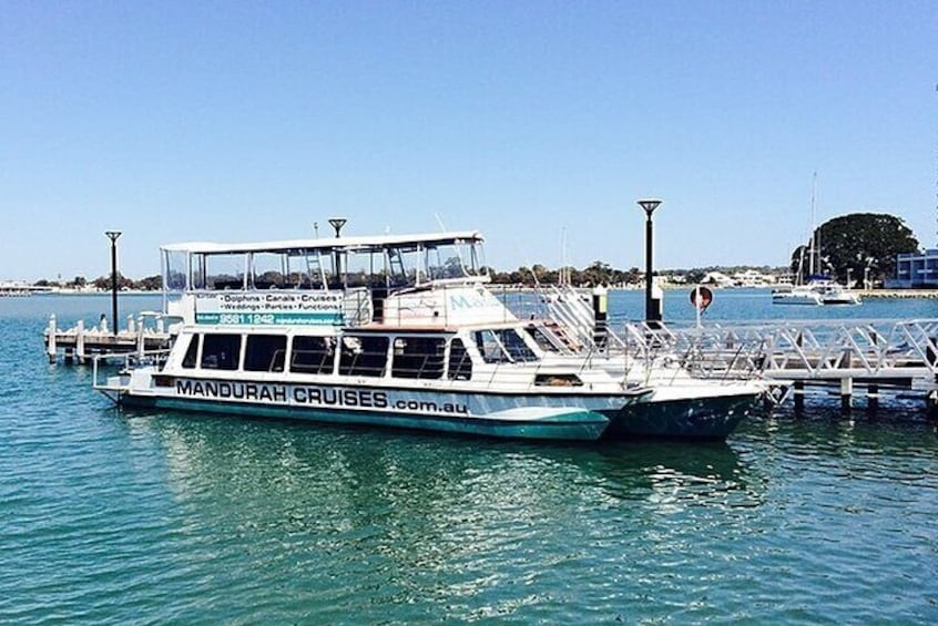A boat docked at a pier with the text "MANDURAH CRUISES.com.au" on its side. 4