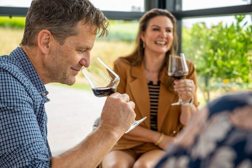 Two people tasting wine in a vineyard setting. 3