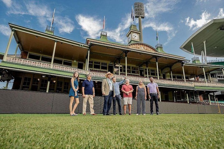 A group of people standing in front of a building with a clock tower and a green roof. 3