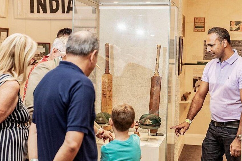 A museum exhibit with cricket bats and a glass display case. 2