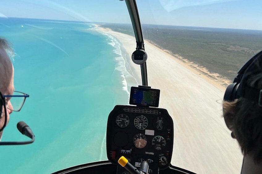 A helicopter cockpit with a view of a beach and ocean. 1